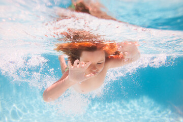 Kids holidays and summer vacation concept. Kid swimming in pool underwater. Child boy swim under...