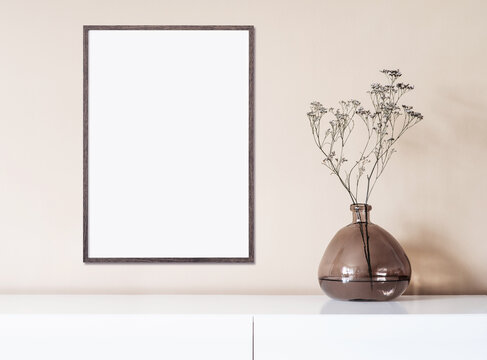 Blank picture frame mockup on beige wall. Vertical artwork template in minimal interior design. View of modern style interior with canvas for painting or poster on wall. Minimalism concept