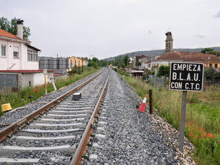 Fototapeta premium Train track at the exit of Monforte de Lemos towards Lugo and a sign next to the rails indicating 