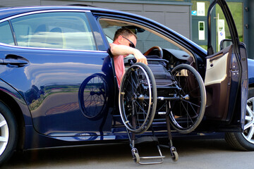 driver with a disability takes a wheelchair out of his car
