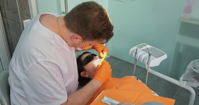 teeth health, patient in sunglasses and mouth expander lies in medical chair during dental treatment procedure by professional doctor stomatologist in dentistry clinic