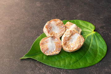 Betel nut or areca nut with betel leaf isolated on dark background. - obrazy, fototapety, plakaty
