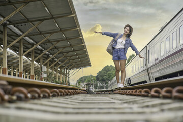 Asian woman balancing on the train rail.  Attractive young woman walking outdoors.