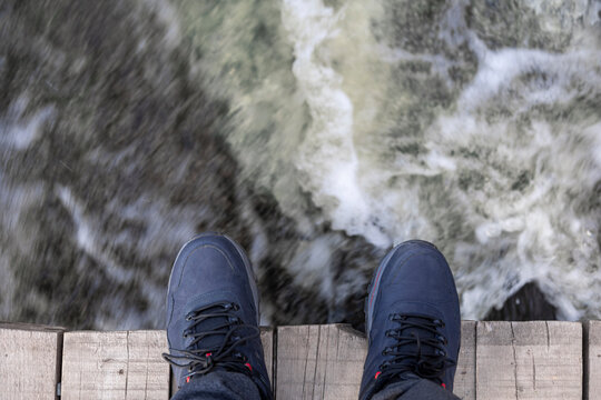 The legs of a man standing on the edge of a precipice.