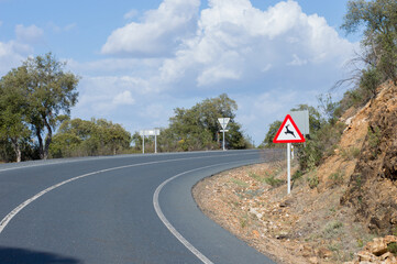 carretera secundaria en entorno rural con señal de peligro por animales salvajes  - obrazy, fototapety, plakaty
