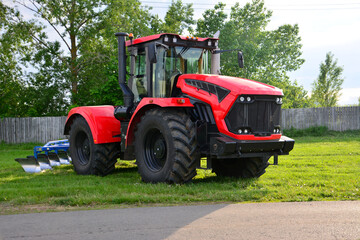 Obraz premium red and black tractor on agricultural field in the countryside