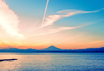 夕暮れ時の美しい富士山と海と飛行機雲