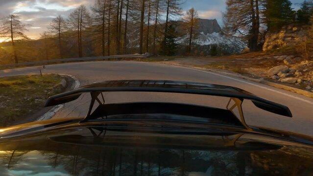 GIAU PASS, DOLOMITES, ITALY, MAY 2022: Stunning panoramic drive up the winding mountain road at beautiful sunset hour. Picturesque gold-lit alpine landscape while driving uphill on a serpentine road.