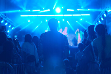 Silhouettes of people in big concert stage. Bright beautiful rays of light