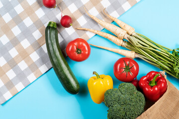 Frsh and healthy vegetables straight grom grocery farm shop in the organic bag exposed on light blue background.