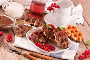 Waffles with chocolate topping, red currant and hazelnuts.