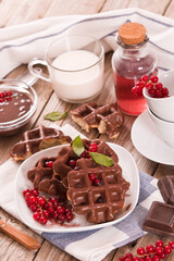 Waffles with chocolate topping, red currant and hazelnuts.