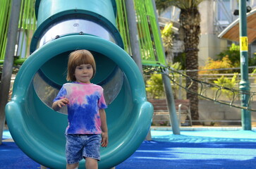 Fototapeta na wymiar Cute boy on the playground. Concept: Kindergarten advertisement, children's vacation, preschool education, travelling, family resort, water park