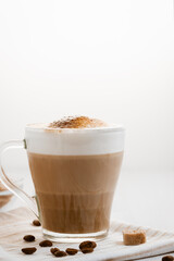 Latte coffee poured in layers with froth and a crispy chocolate top on a light kitchen table. Vertical image with copy space