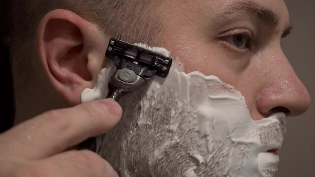 A person shaves with a razor, shaving foam is applied to the skin. Take care of the appearance, shave. Application of shaving foam