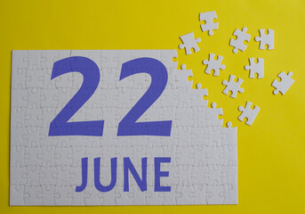 22 june calendar date on a white puzzle with separate details. Puzzle on a yellow background with a...