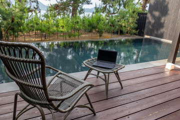 ワーケーション　イメージ　プールのある海辺のテラスで　remote working at poolside terrace with rattan furniture