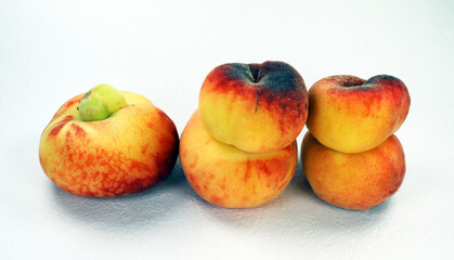 Unusual Donut Peach isolated on white. Ripe fresh tasty flat peaches of unusual shape, fused two by two together close-up. paraguayo