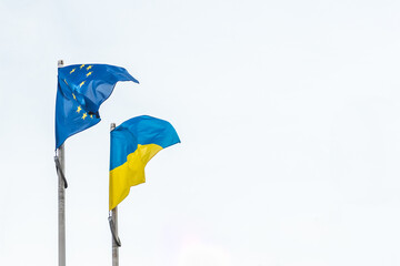 Flag of of Ukraine and European Union waving together in the white sky, copy space