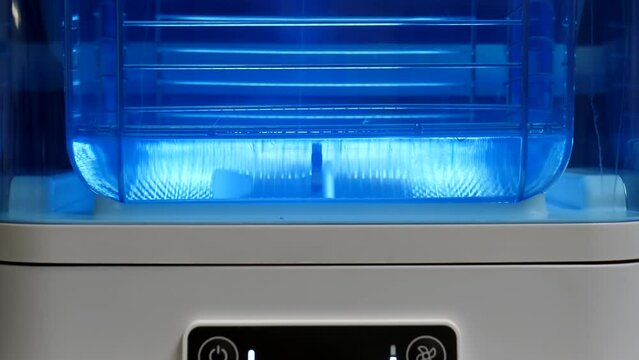Tilt up shot of device with water container. Circulating liquid dissolving, removing PVA, Poly vinyl alcohol from printed 3D object floating freely inside.