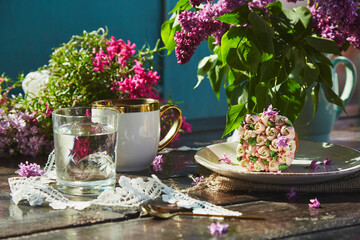 Aesthetic garden picnic with a cup of coffee, beautiful cupcake, glass of water, flowers and lace...