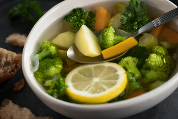 Vegetarian vegetable soup with carrots, broccoli and parsley in a light bowl on a metal tray on a wooden table