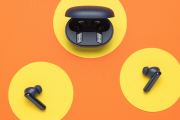 Wireless headphones and a box on a yellow-orange abstract background. A popular wireless gadget.