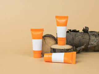 Orange tubes with white letterheads on an old tree on a beige background.