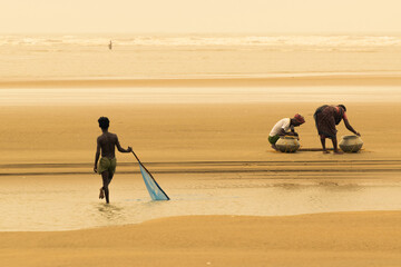 TAJPUR, WEST BENGAL, INDIA - JUNE 22ND, 2014 : A fisherman's son catching fish with his parents...