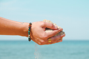 Fototapeta na wymiar Mains d'une personne portant du sable fin face à la mer.
