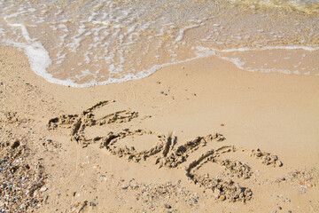 Inscription love sur sable fin et vague.