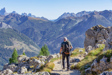 Active senior man hiking in Dolomiti mountains with backpack, enjoying his adventure. Carezza,...
