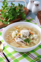 Soup with chicken, vegetables and egg noodles in white bowl close-up, Vertical format