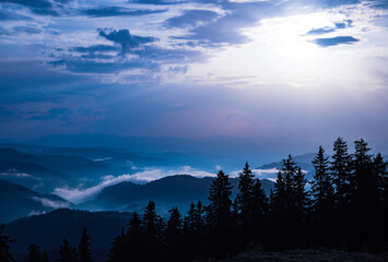 Cloudy weather over hills covered with spruce forests in Rhodope Mountains and fog between mountain ranges