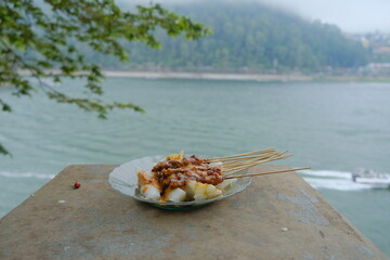 A plate of satay meat on a lake background