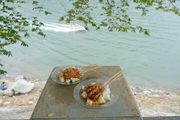 A plate of satay meat on a lake background