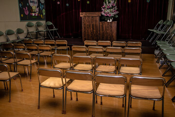 Empty school auditorium filled with various chairs for teachers and students