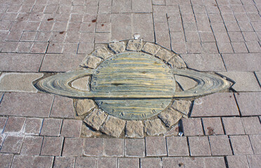 Bronze Saturn on the ground near the monument to Nicholas Copernicus