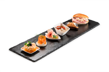Black stone rectangular tray with shrimp tartare snack cannoli swordfish ravioli with robbiola tartina nordica mousse aubergine