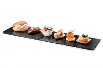 Black stone rectangular tray with shrimp tartare snack cannoli swordfish ravioli with robbiola tartina nordica mousse aubergine