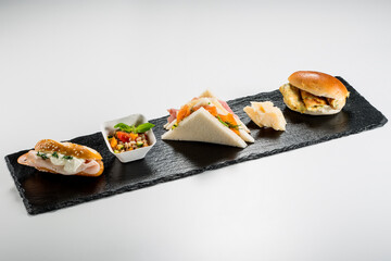 Black stone rectangular tray with snack Pretzel turkey flaky cheese sandwiches salmon pearl spelled vegetables milk sandwiches omelette