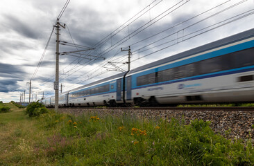 Schnellzug in grün blühender Landschaft mit Wolkenhimmel
