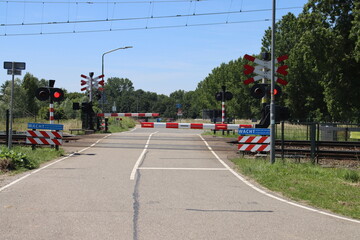 Barriers closed with red lights at railway crossing close to Dordrecht