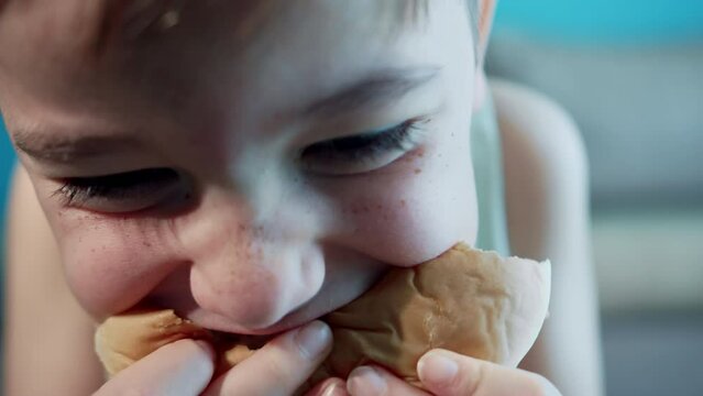 Close-up mouth of a hungry man with braces on his teeth greedily bites his hamburger, eats hamburger in a restaurant, enjoying a delicious juicy burger, an adult guy appetizingly bites a hamburger. 4k