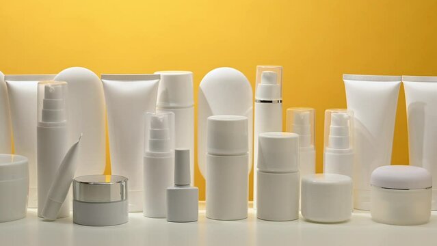 Jar, bottle and empty white plastic tubes for cosmetics on a yellow background. Packaging for cream, gel, serum, advertising and product promotion