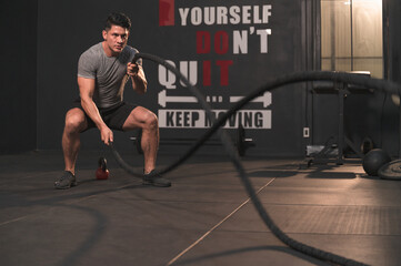 Obraz premium Caucasian sport man with rope doing exercise in functional training fitness gym
