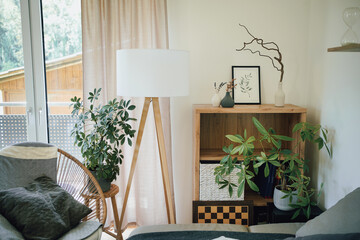 Modern interior in natural colors with a tripod lamp, plants and furniture. 