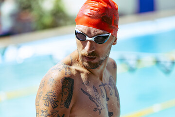 Closeup young handsome man, professional swimmer in goggles and swimming cap getting ready to swim, outdoors. Sport, power, energy, style, hobby concept. - obrazy, fototapety, plakaty