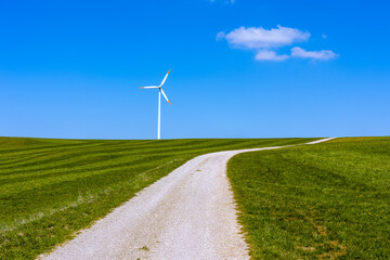 A path through rural landscape with a wind turbine in the background