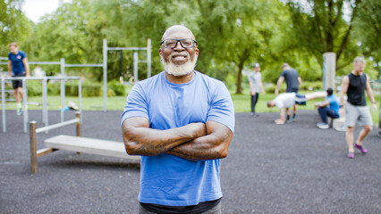 Portrait of confident, muscular black senior man with his arms folded smiling to camera - Powered by Adobe